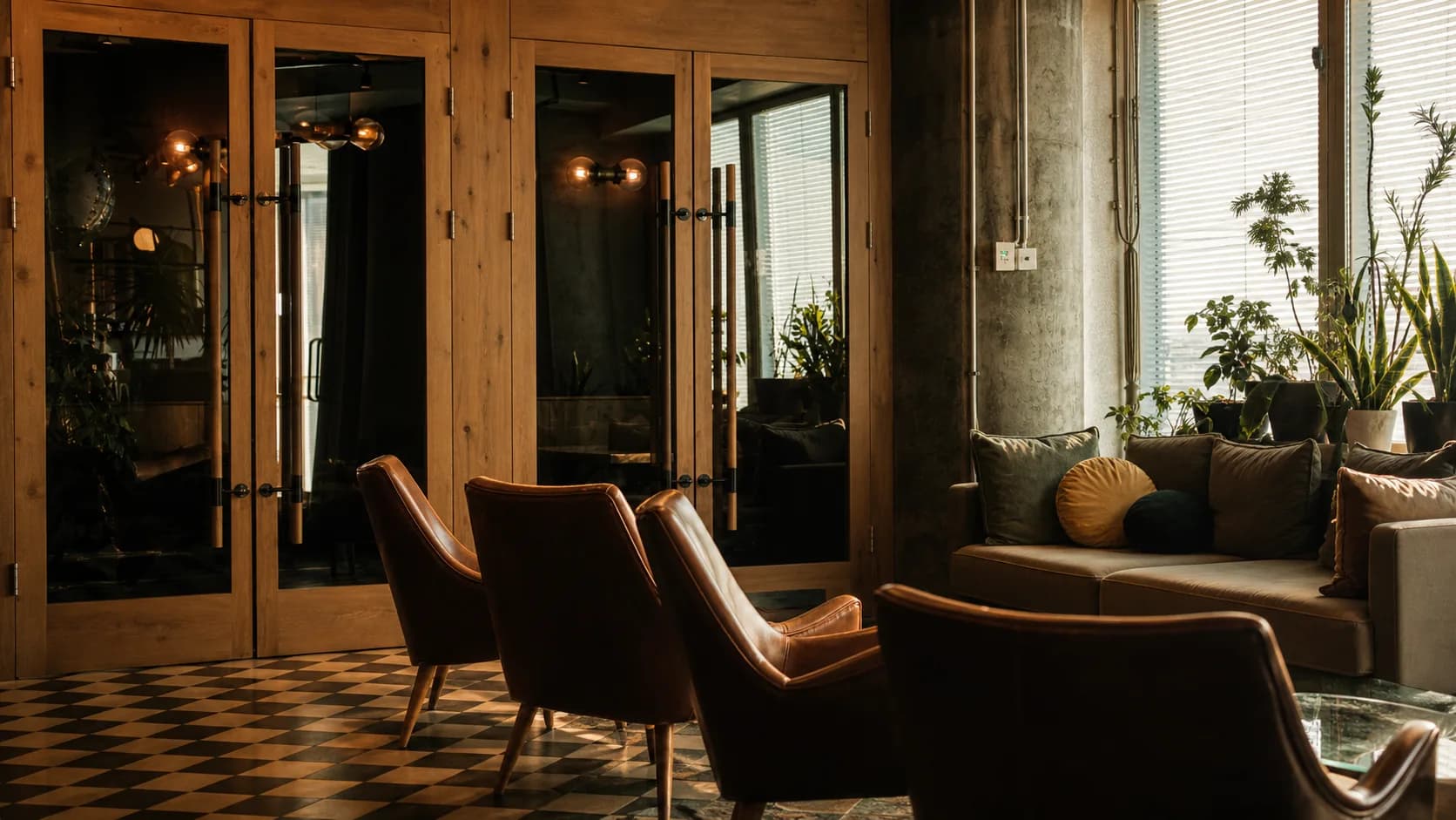 A warm timber, leather, and concrete community lounge at Grandeur Living